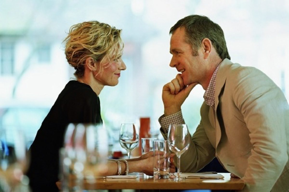 Couple sitting face-to-face at restaurant table, smiling